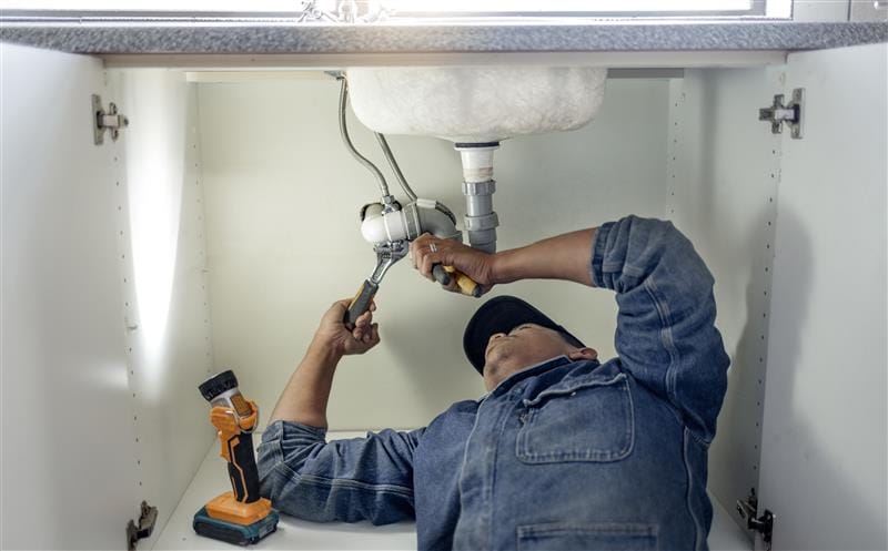 Plumber repairing pipes beneath a bathroom sink in Altamonte Springs