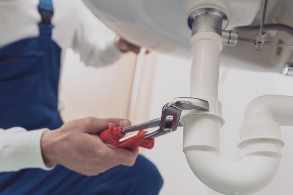 Plumber repairing a white drain pipe beneath a sink in Altamonte Springs