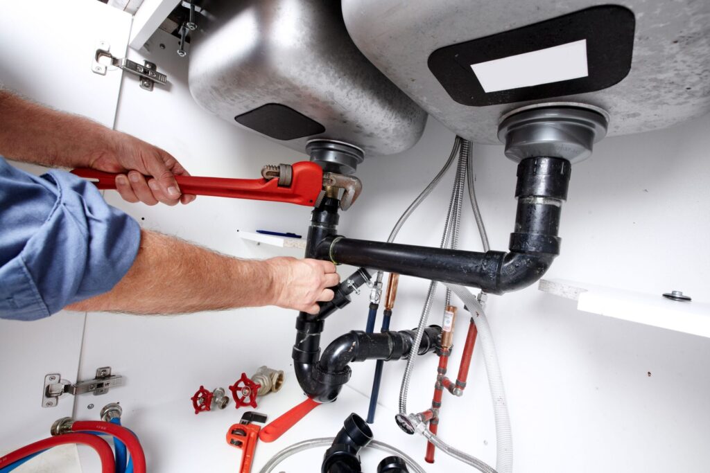 Plumber repairing drain pipes beneath a kitchen sink in Altamonte Springs