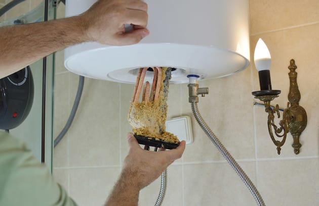 Technician removing mineral buildup from a water heater in Altamonte Springs